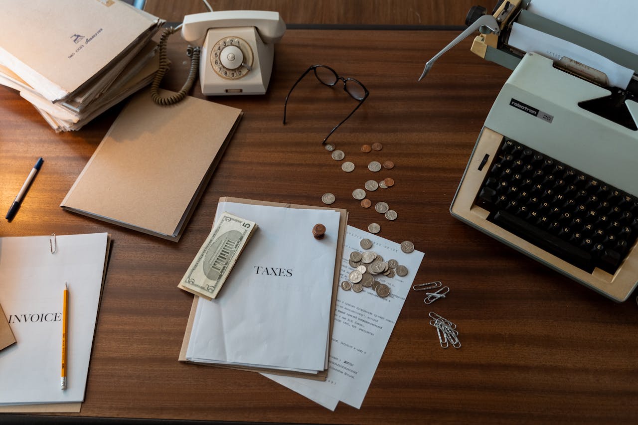 Vintage workspace with typewriter, documents, and telephone on a wooden desk, evoking a classic office setting.